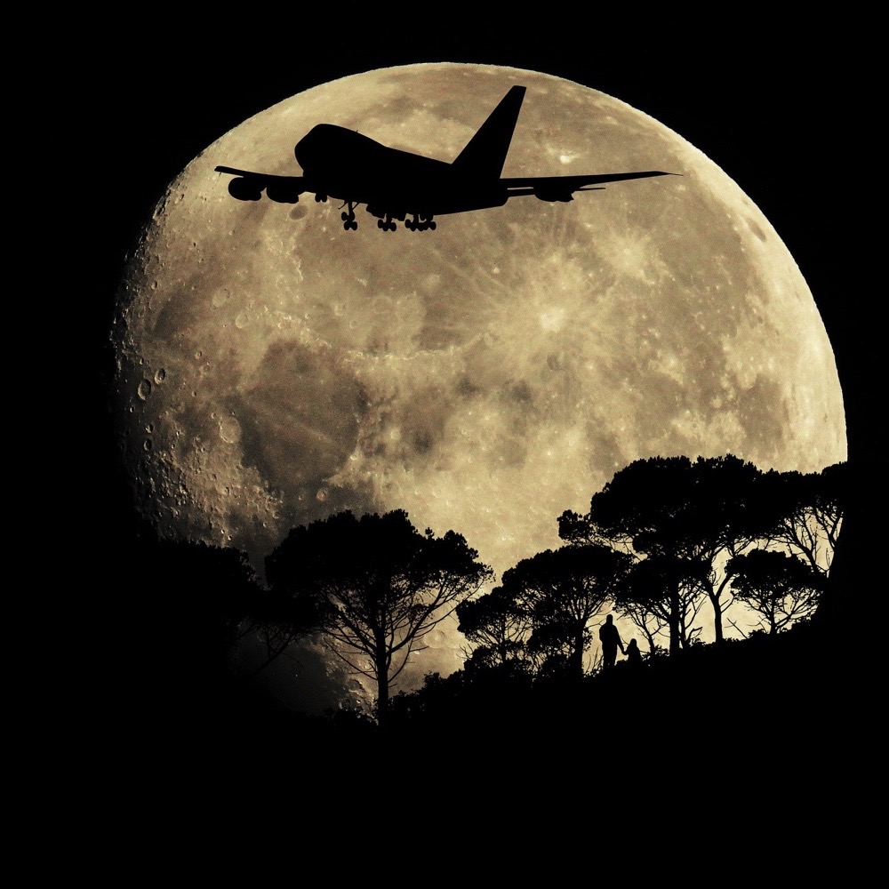 A plane flying with a large Moon as the background